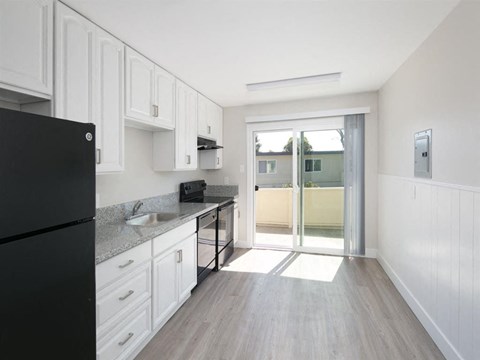 a kitchen with white cabinets and a sliding glass door