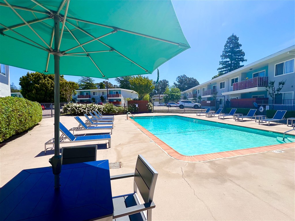 the pool area of a hotel with chairs and umbrellas