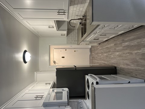 A modern kitchen with a black fridge and white cabinets.