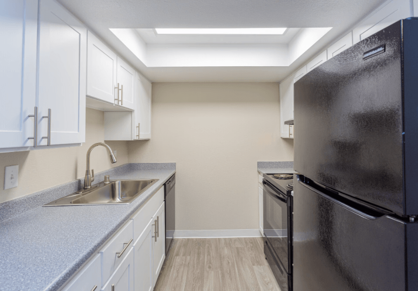 a kitchen with white cabinets and black appliances