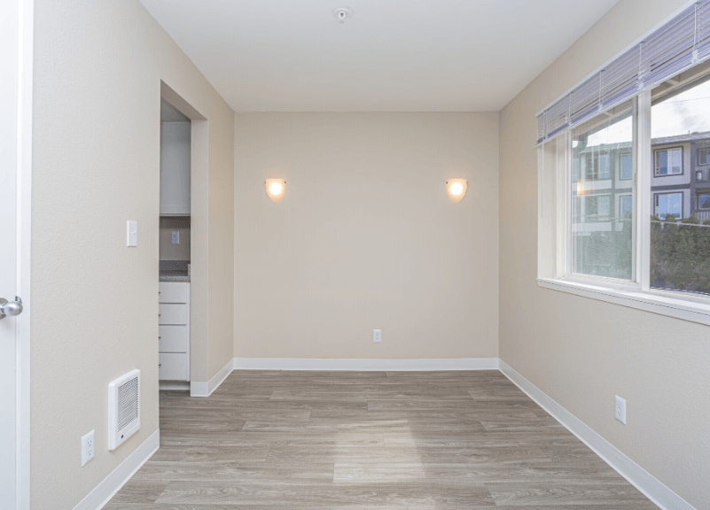 a bedroom with hardwood flooring and a large window