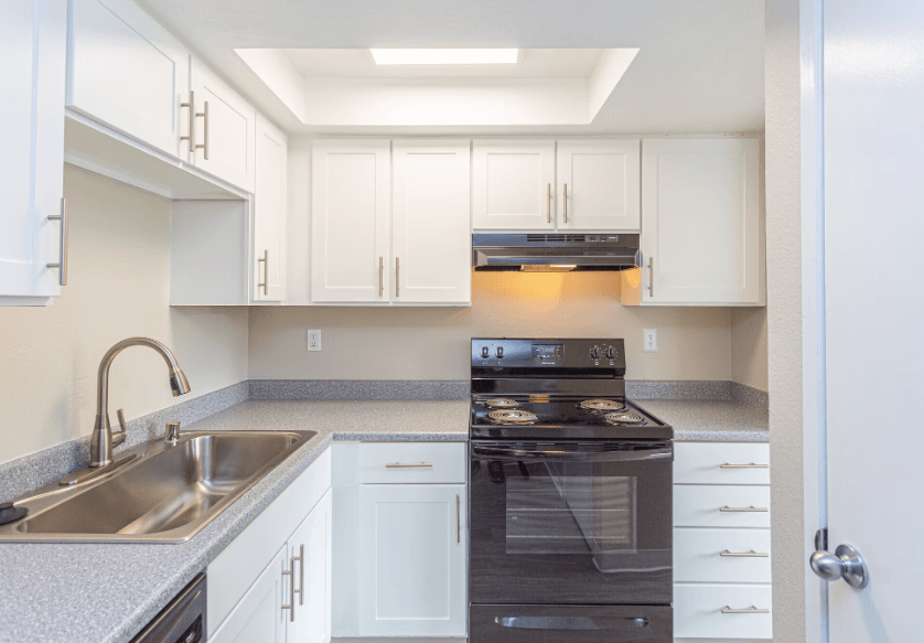 a kitchen with white cabinets and black appliances