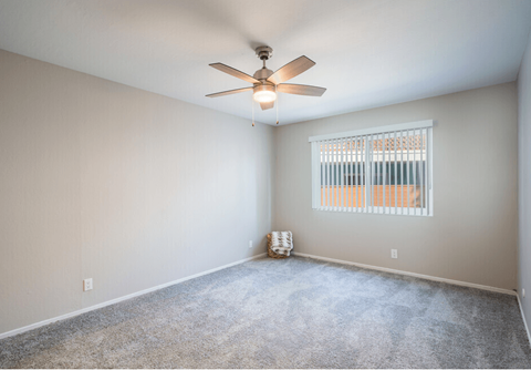 an empty living room with a ceiling fan and a window