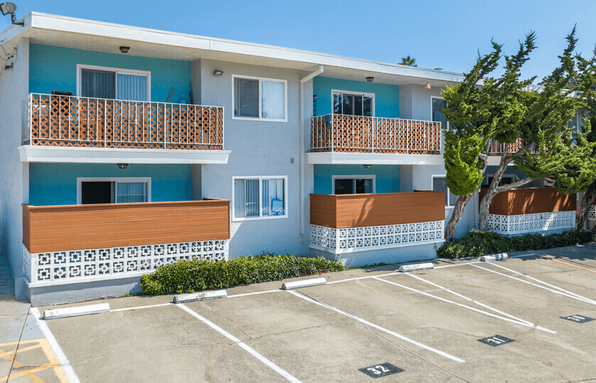 a blue and white apartment building with a parking lot in front of it
