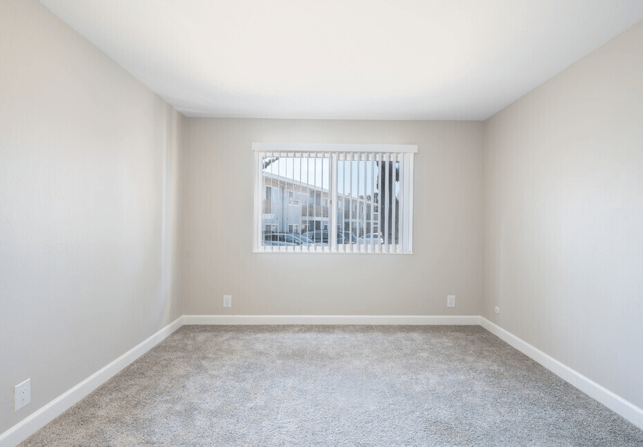 a bedroom with a large window and a carpeted floor