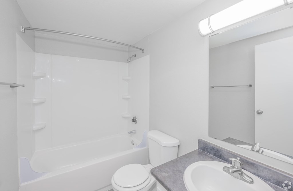 A white bathroom with a toilet, sink, and bathtub.