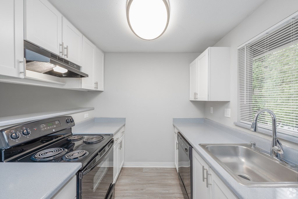 A kitchen with white cabinets and a stove top oven.