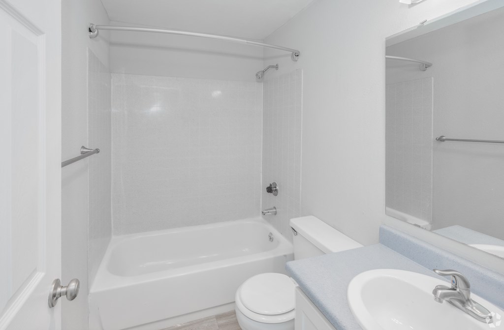 A white bathroom with a toilet, sink, and bathtub.