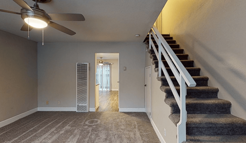 a living room with stairs and a ceiling fan
