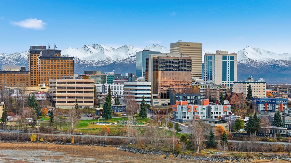 A cityscape with buildings and snow-capped mountains in the background.
