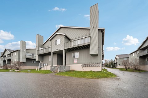 A large grey building with a balcony and a smaller building to its left.