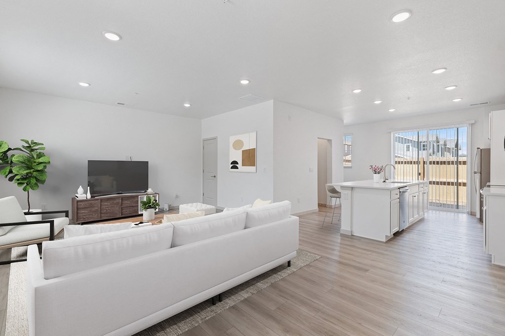 a living room with a white couch and a kitchen with a tv