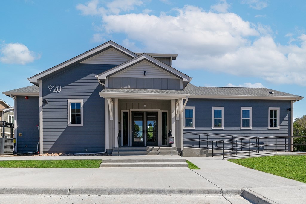 the front of a blue house with a porch and a sidewalk