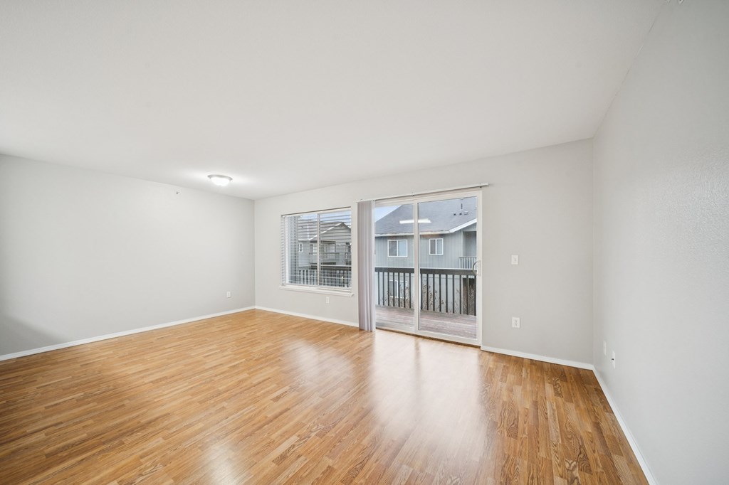A room with wooden flooring and a window overlooking a balcony.