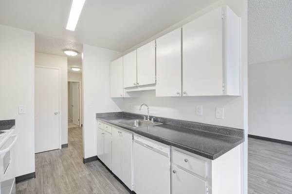 A kitchen with white cabinets and a black countertop. A kitchen with white cabinets and a black countertop at Royal Pines Apartments, Beaverton