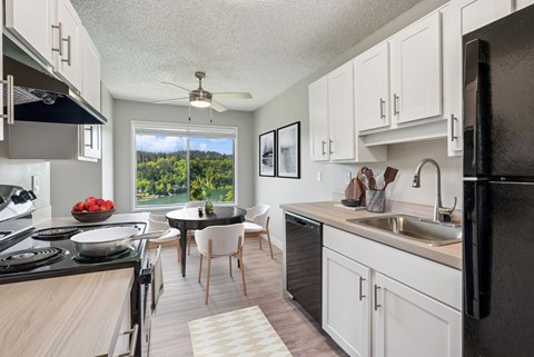 A kitchen with black appliances and white cabinets.