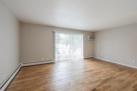 an empty living room with wood flooring and a sliding glass door