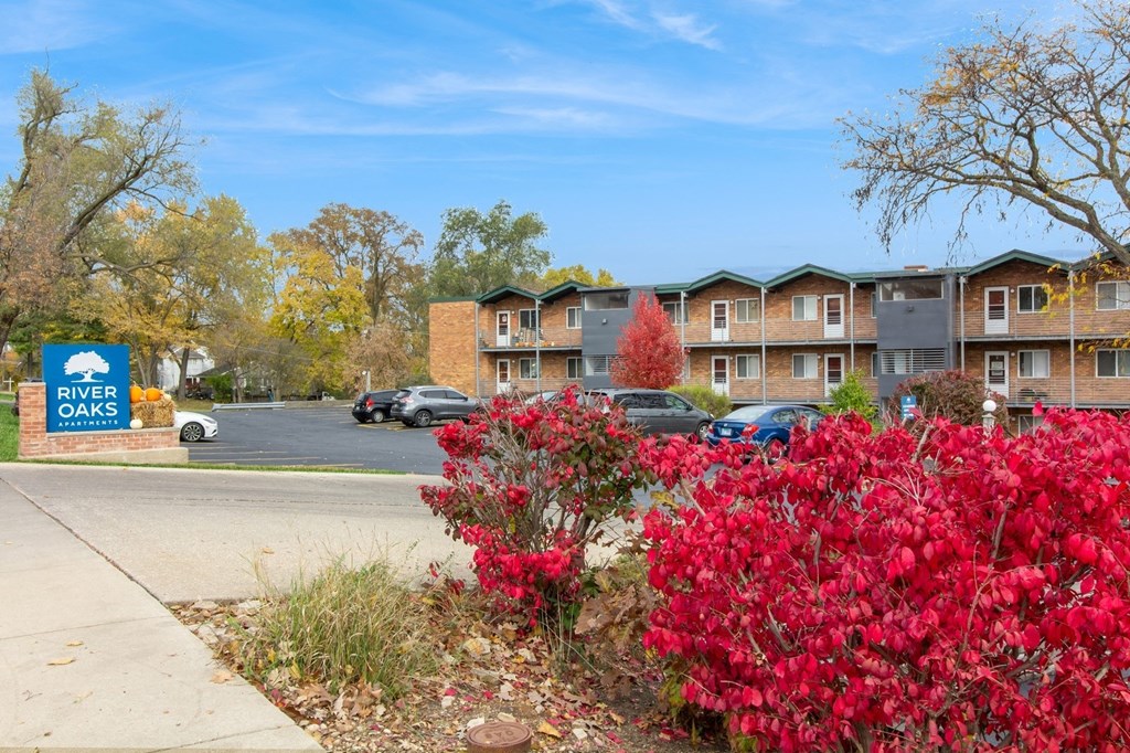 an apartment building with red flowers in front of a sidewalk at River Oaks, North Aurora, Illinois