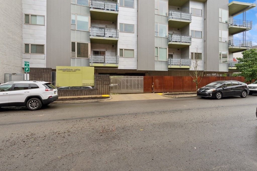 A white car is parked on the side of the road in front of a building.