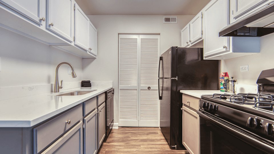 a kitchen with white cabinets and black appliances at The View Apartments St Charles, St Charles, IL