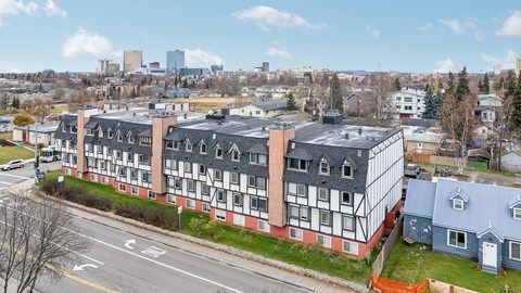 A large building with a red and white facade sits in the foreground of a city street.