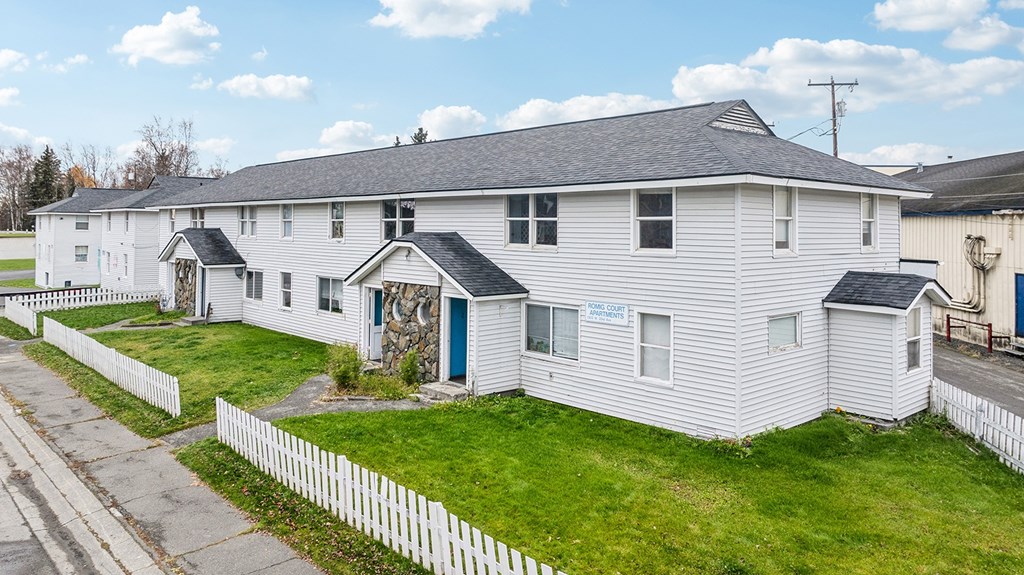 A white building with a blue door and a sign on the window.