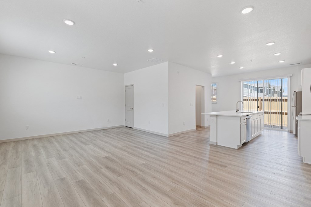the living room and kitchen of a new home with white walls and wood flooring
