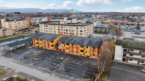 A parking lot in front of a large building with orange and black stripes.
