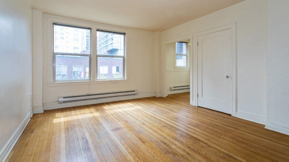 the living room of an empty apartment with wood floors and white walls