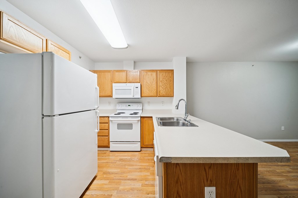 A white refrigerator is in a kitchen with wooden cabinets and a white counter top.