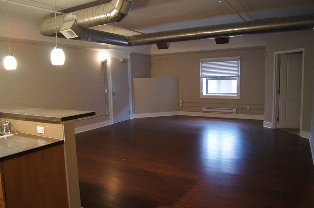 an empty living room with wood floors and a window