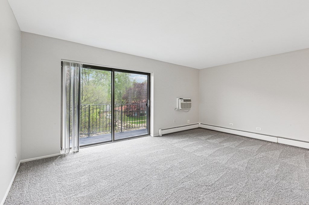 A room with a carpeted floor and a sliding glass door.