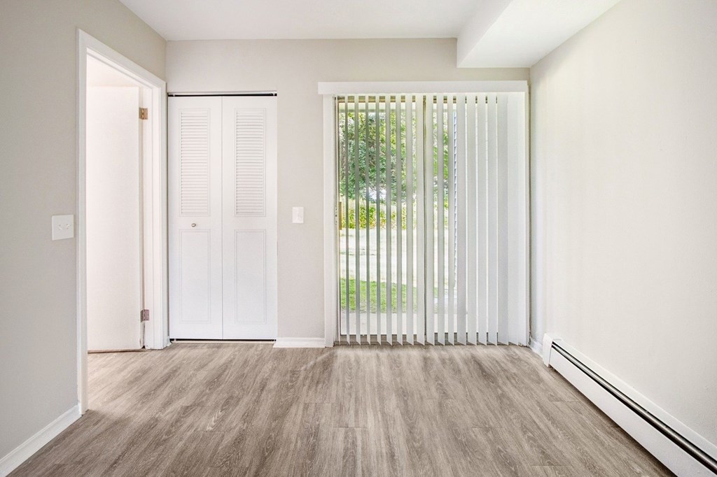 A room with a sliding door and a window with blinds.