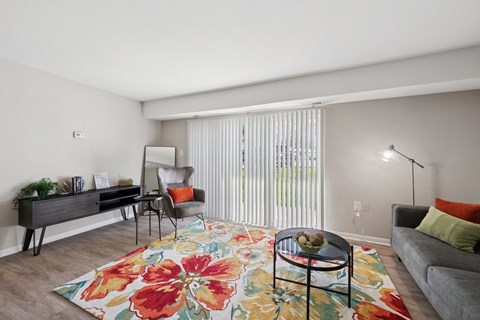 A living room with a floral rug and a grey couch.