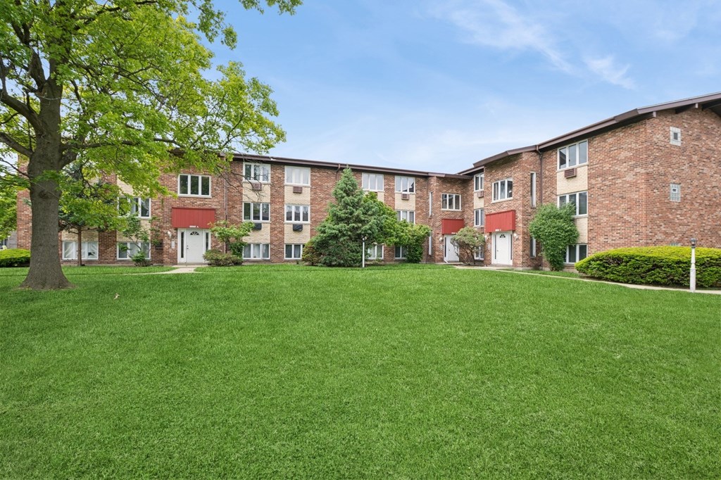 A grassy area in front of a brick apartment building.
