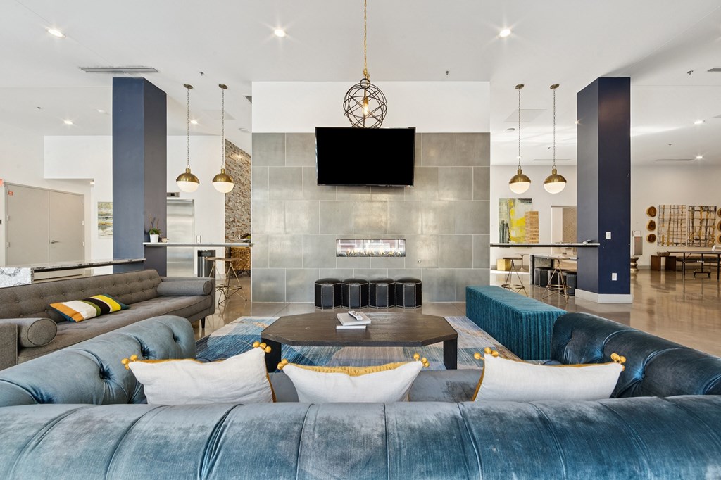 A modern living area with a blue velvet sofa and a television mounted on the wall.