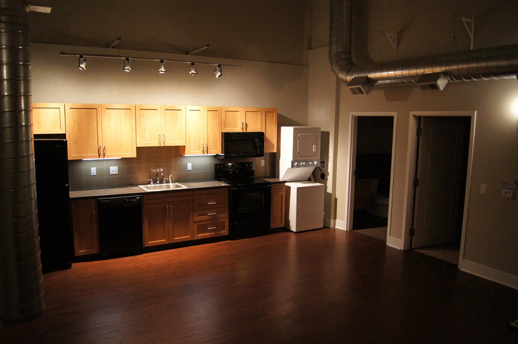 an empty kitchen with wooden cabinets and black appliances
