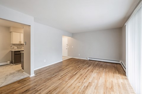 an empty living room with wood flooring and white walls