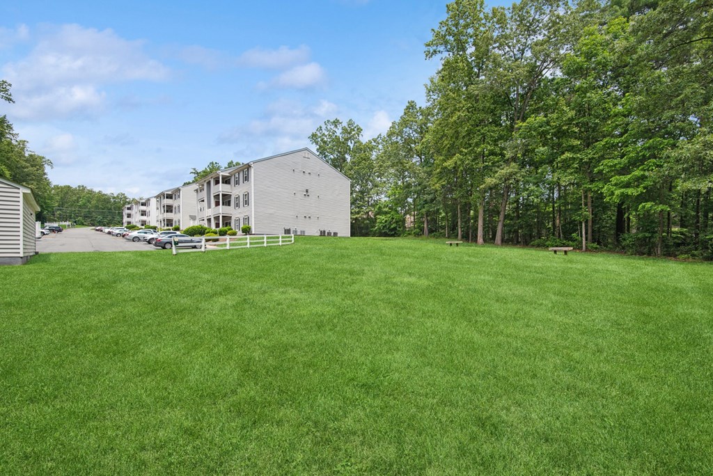 A large grassy field with apartment buildings and trees in the background
