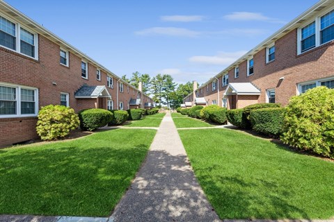 a walkway between two rows of brick apartment buildings