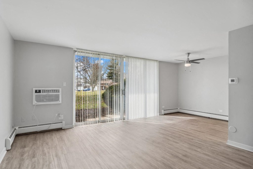 an empty living room with a sliding glass door to a balcony at The Reserve on Washington, Naperville