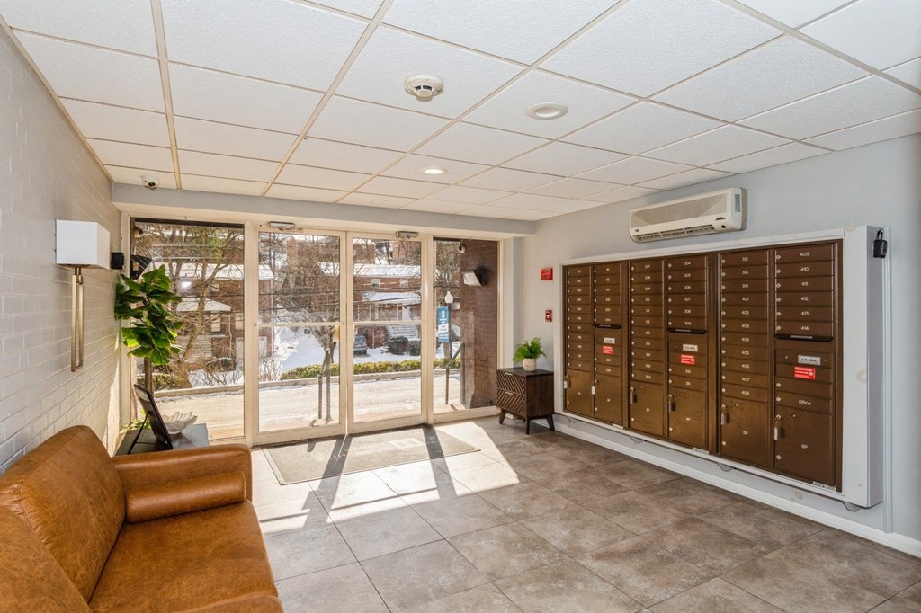 A room with a brown couch and a wall of mailboxes.