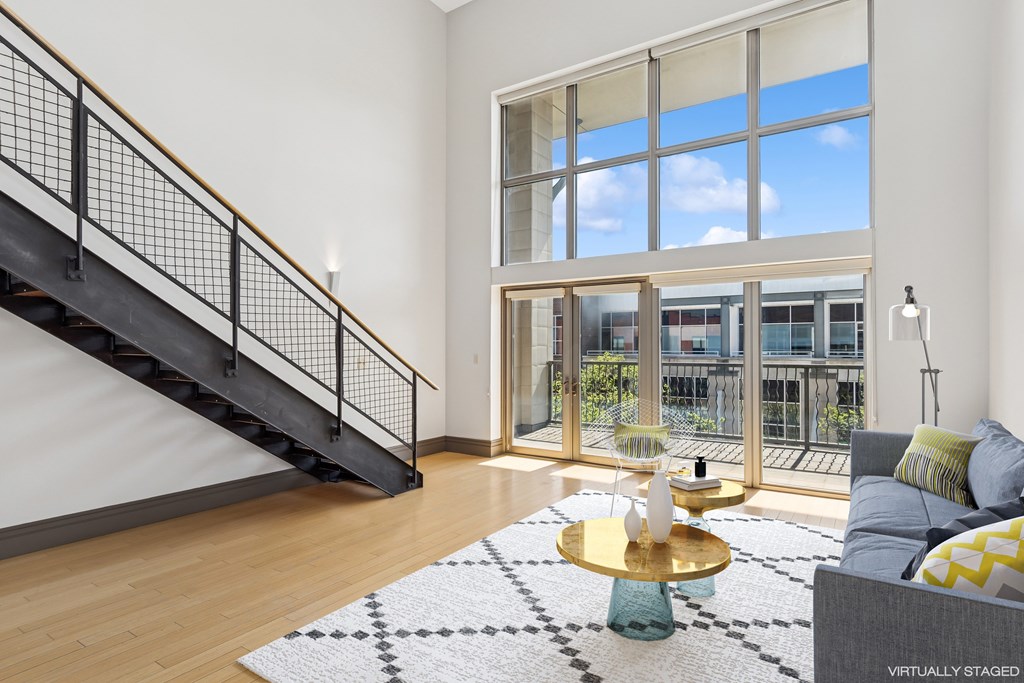 A living room with a staircase and a large window.