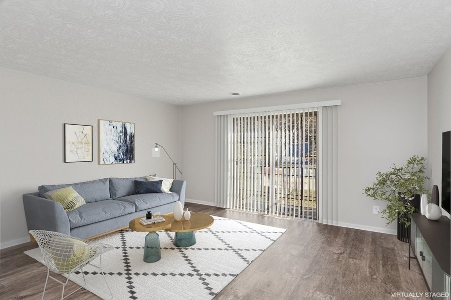 A living room with a grey couch, a yellow chair, a coffee table, and a rug.