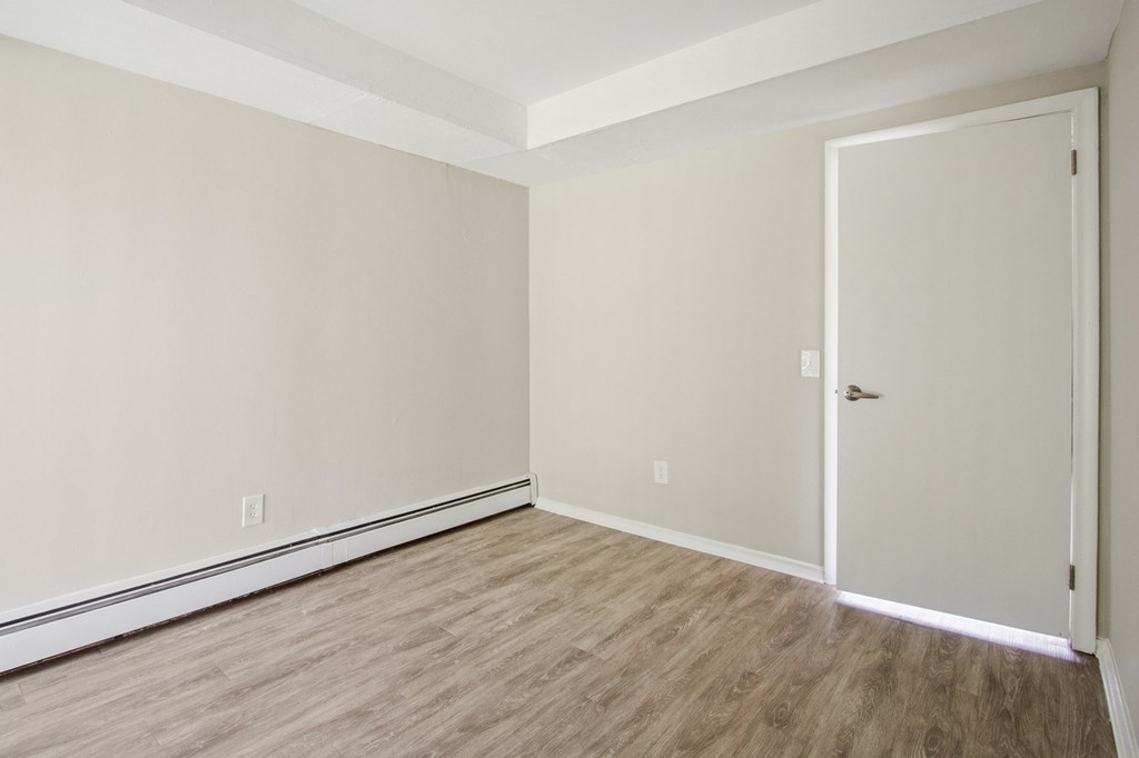 A room with a white door and wooden flooring.