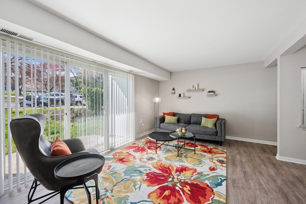 A living room with a grey couch, a black chair, and a floral rug.