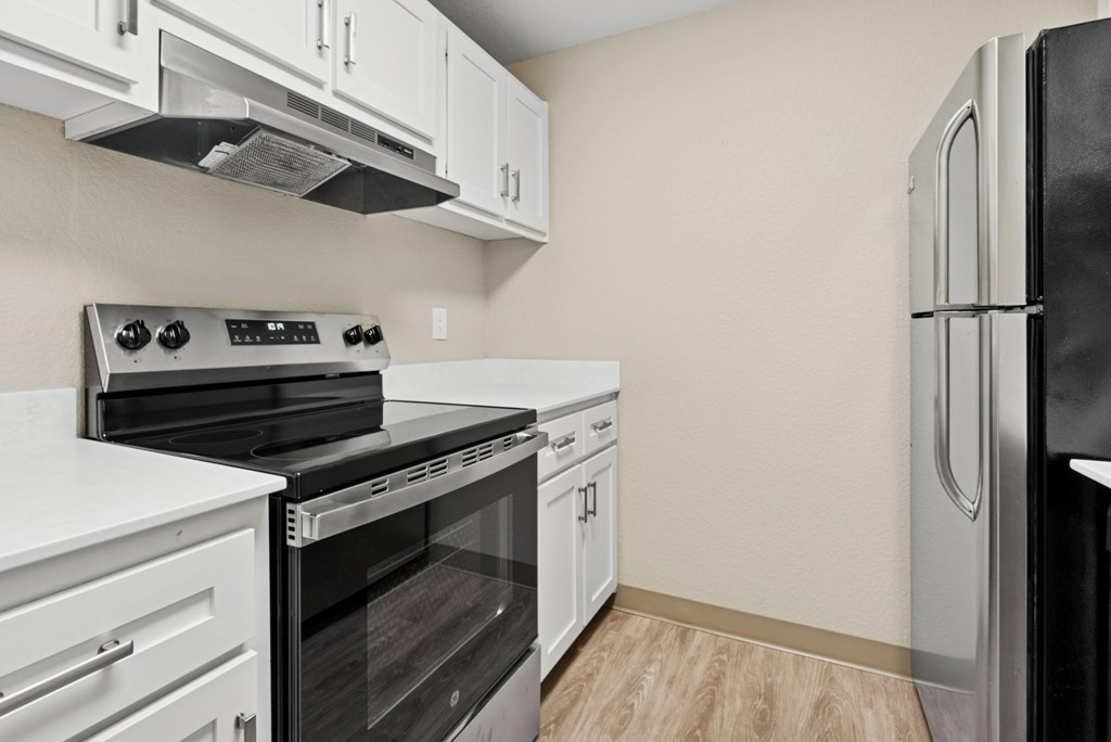 A kitchen with white cabinets and a black refrigerator.