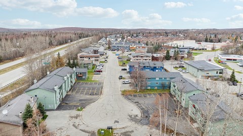 A parking lot is surrounded by buildings and trees.