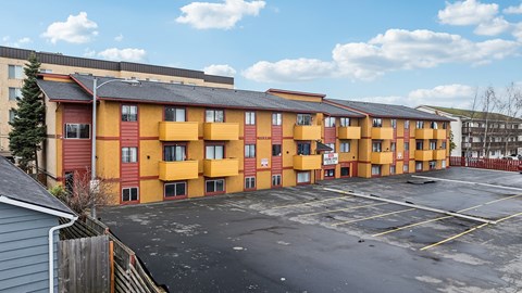A parking lot in front of a row of apartment buildings.