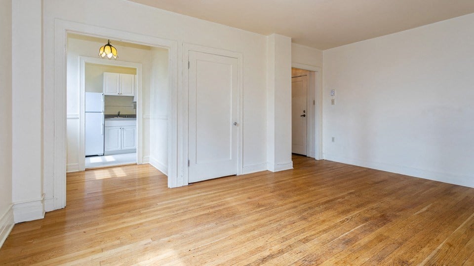 an empty living room with wood floors and white walls